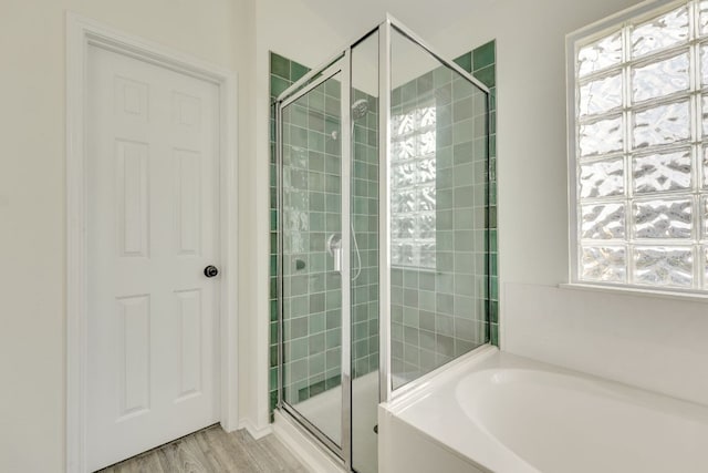 bathroom featuring wood finished floors, a stall shower, and a garden tub