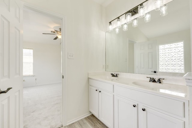 full bathroom with double vanity, a sink, a ceiling fan, and baseboards