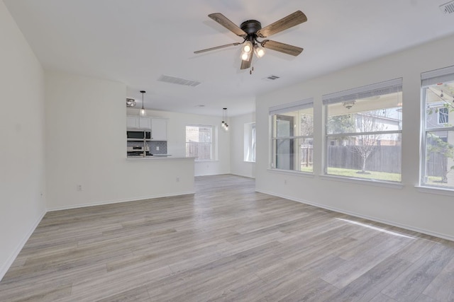 unfurnished living room featuring light wood finished floors, baseboards, visible vents, and a ceiling fan