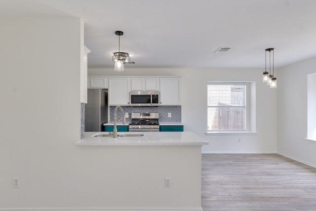 kitchen with white cabinetry, light countertops, appliances with stainless steel finishes, backsplash, and decorative light fixtures