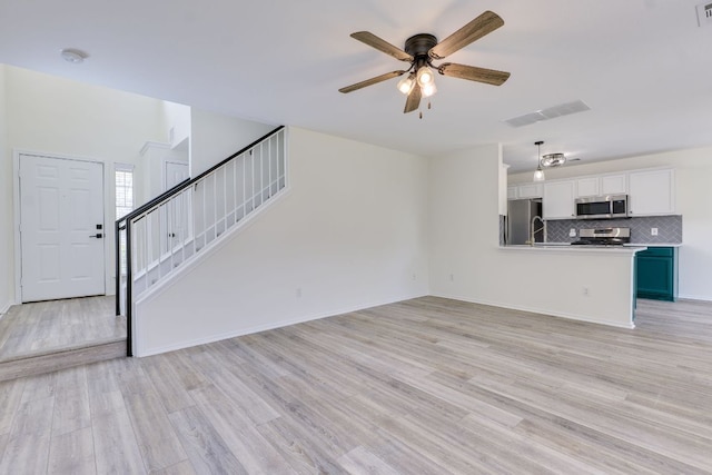 unfurnished living room with light wood finished floors, visible vents, stairway, and a ceiling fan