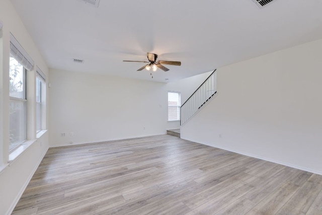 unfurnished living room with light wood-style flooring, visible vents, and stairway