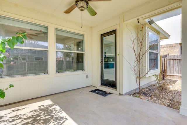 entrance to property with a patio area, ceiling fan, and fence