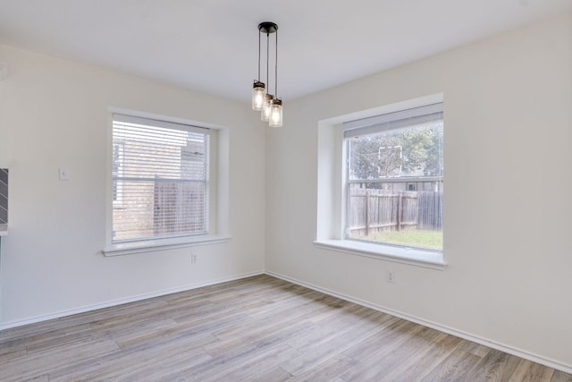 spare room with a wealth of natural light, baseboards, and wood finished floors