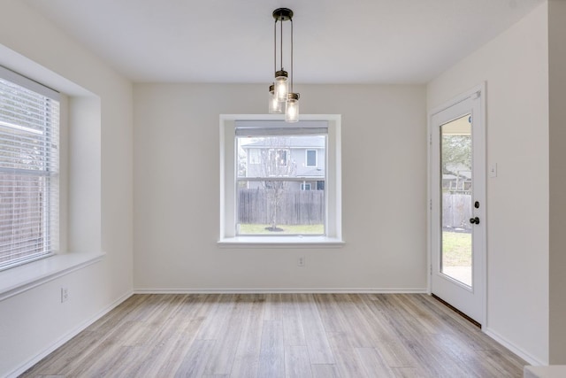 unfurnished dining area with light wood-type flooring and baseboards