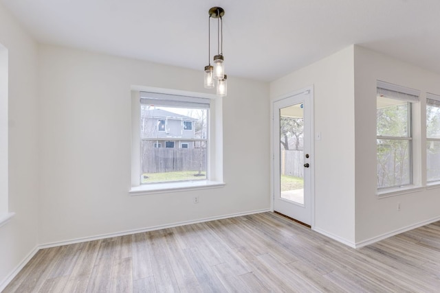 unfurnished dining area featuring light wood finished floors and baseboards