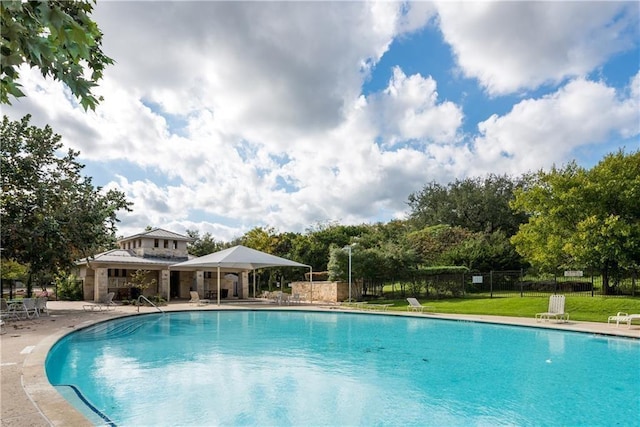 pool featuring a patio area, fence, and a lawn