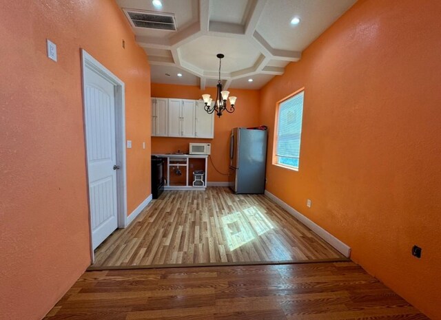 kitchen featuring visible vents, white microwave, light wood-style floors, freestanding refrigerator, and white cabinetry