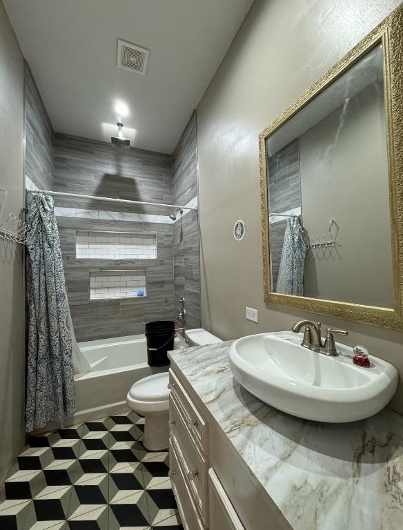 full bath featuring toilet, visible vents, shower / bath combo with shower curtain, and vanity