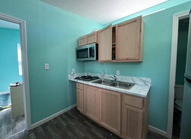 kitchen with stainless steel appliances, light countertops, dark wood-type flooring, light brown cabinets, and a sink