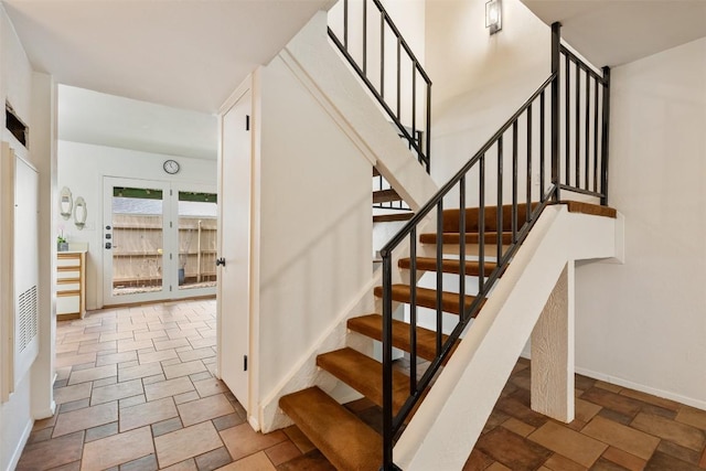 staircase featuring baseboards and stone tile floors