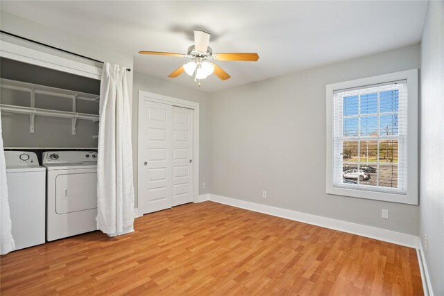 washroom featuring laundry area, baseboards, light wood-type flooring, and washer and clothes dryer