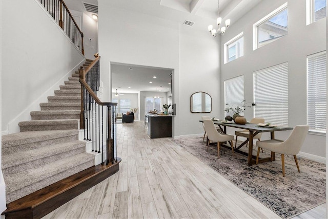 interior space with stairs, a towering ceiling, a notable chandelier, and wood finished floors