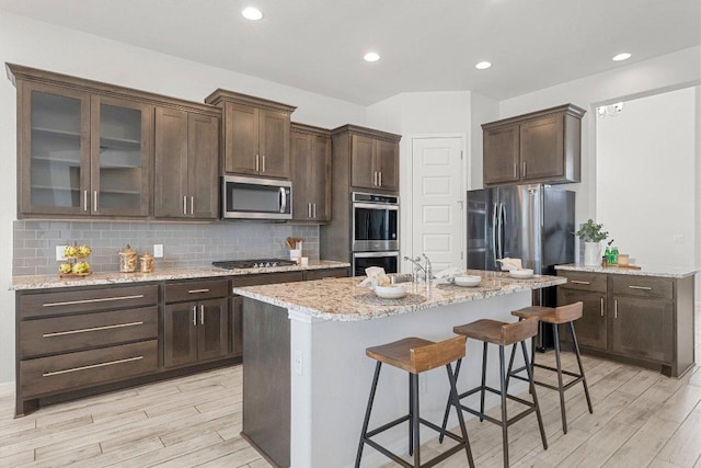 kitchen featuring appliances with stainless steel finishes, dark brown cabinetry, and tasteful backsplash