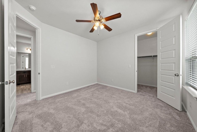 unfurnished bedroom with a spacious closet, baseboards, and carpet