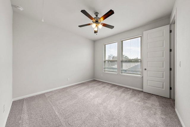 spare room with carpet, a ceiling fan, and baseboards