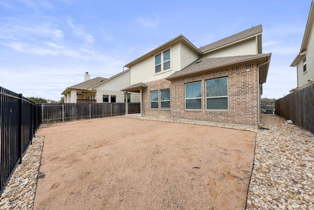 back of property featuring stucco siding, a fenced backyard, a patio area, and brick siding