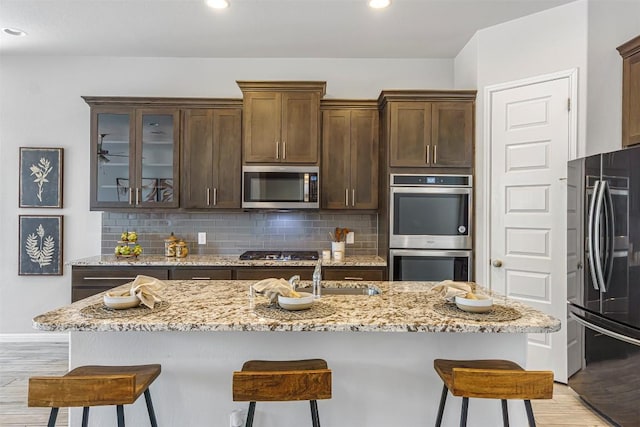 kitchen with light wood-style floors, appliances with stainless steel finishes, a sink, and a breakfast bar area