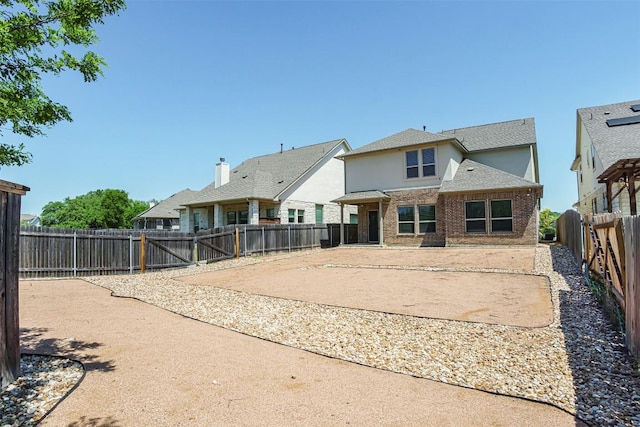 rear view of property featuring a patio area, brick siding, and a fenced backyard
