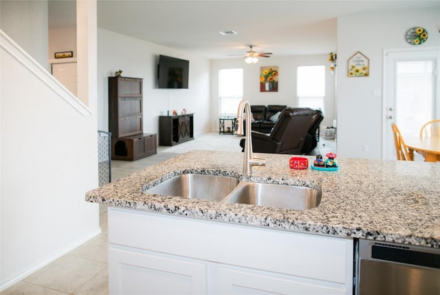 kitchen with a sink, white cabinets, light stone countertops, and ceiling fan
