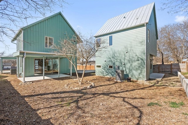 back of house featuring metal roof, a standing seam roof, fence, cooling unit, and a patio area