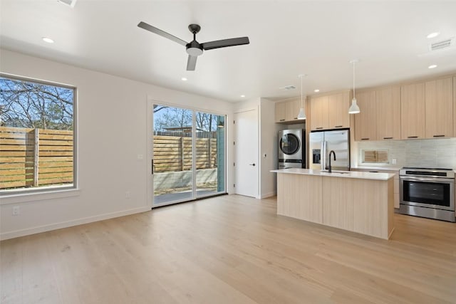 kitchen with visible vents, stacked washer / dryer, modern cabinets, stainless steel appliances, and light brown cabinetry