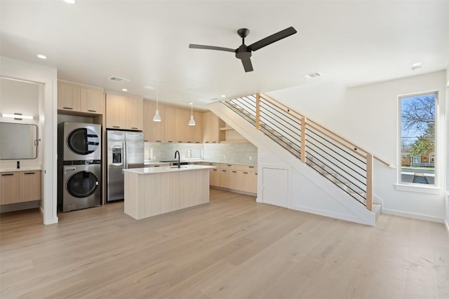 kitchen with stacked washer and dryer, stainless steel fridge, light brown cabinets, and modern cabinets