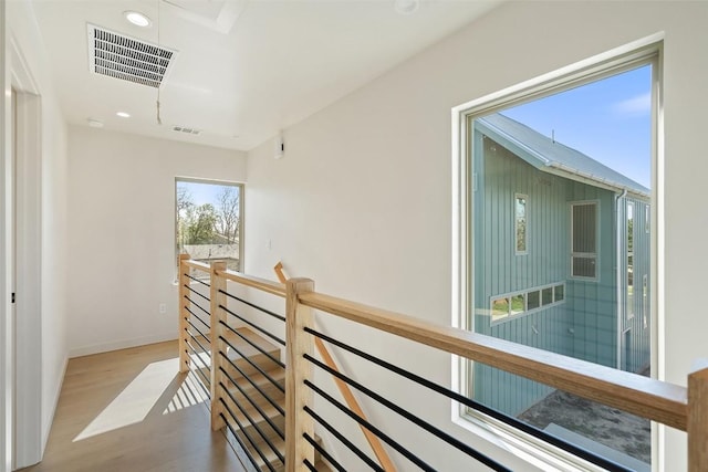 hallway with baseboards, visible vents, wood finished floors, an upstairs landing, and recessed lighting