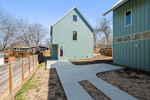 rear view of property with a patio, board and batten siding, and fence private yard