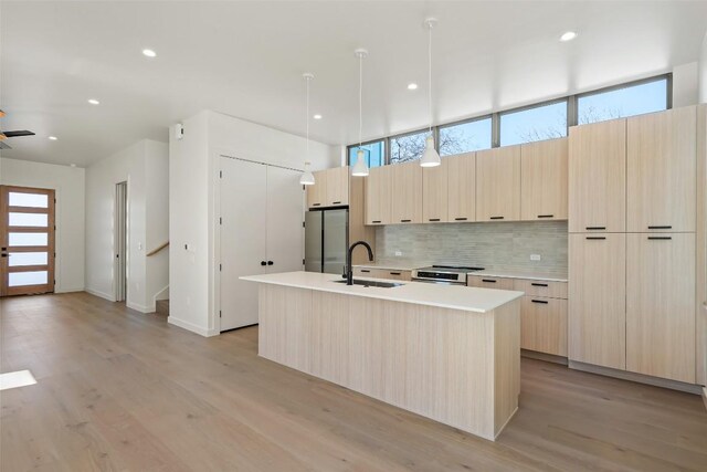 2912 Pecan Springs Rd, Austin, TX 78723 - kitchen with modern cabinets, appliances with stainless steel finishes, light brown cabinetry, decorative backsplash, and light wood-type flooring