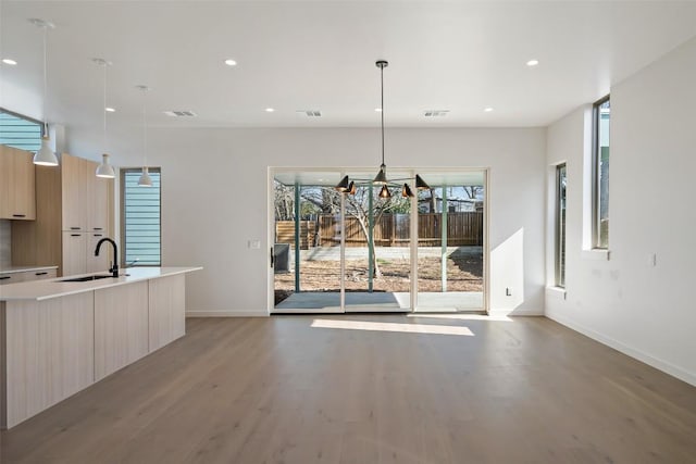 unfurnished dining area featuring light wood-type flooring, visible vents, a sink, and recessed lighting