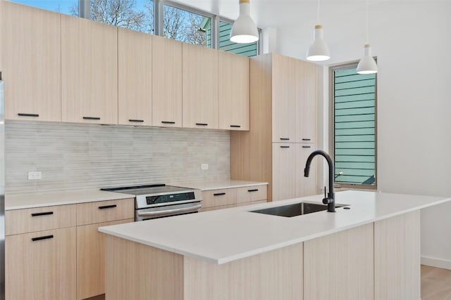 kitchen featuring light brown cabinets, stainless steel electric range oven, a sink, and modern cabinets