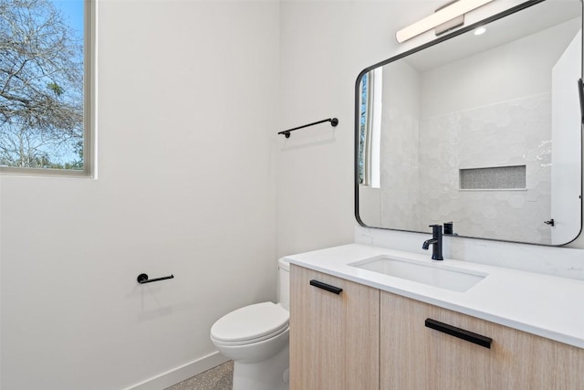 bathroom featuring toilet, baseboards, and vanity