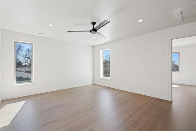 spare room with visible vents, plenty of natural light, attic access, and light wood-style floors