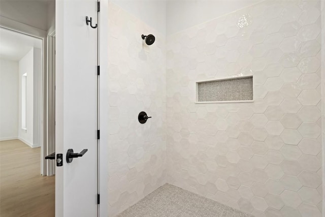 bathroom featuring a tile shower and wood finished floors