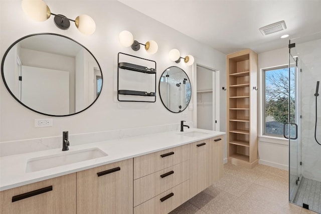 bathroom with double vanity, a stall shower, a sink, and visible vents