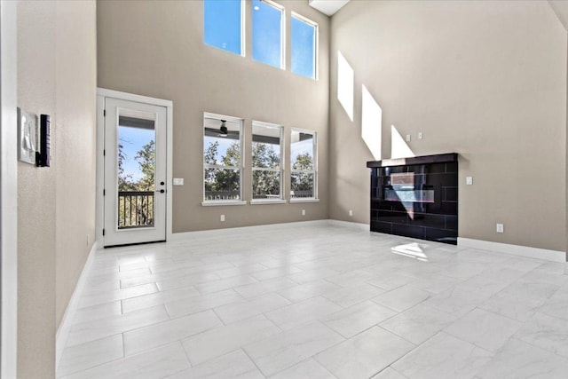 17503 Panorama Dr, Dripping Springs, TX 78620 - unfurnished living room featuring plenty of natural light, a towering ceiling, marble look tile flooring, and baseboards