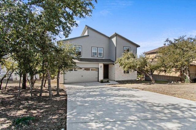 view of front of property featuring a garage, stone siding, and concrete driveway