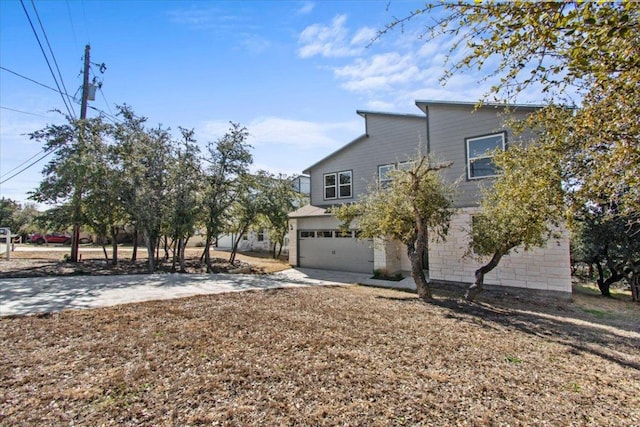 view of front of home with driveway, stone siding, and a garage