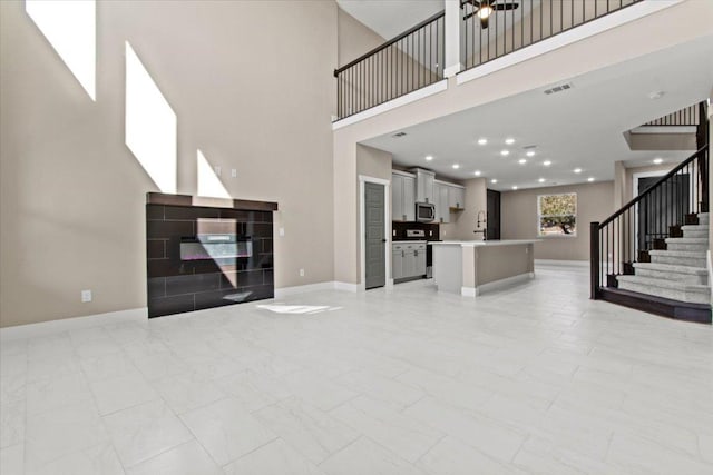 17503 Panorama Dr, Dripping Springs, TX 78620 - unfurnished living room with stairway, baseboards, a towering ceiling, and light marble finish flooring