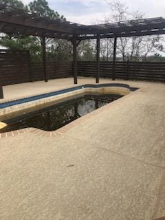 pool with a patio and fence