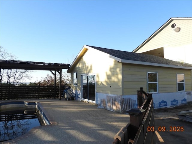 view of side of property featuring roof with shingles and fence