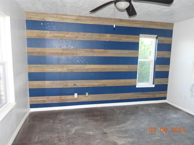 spare room with baseboards, a textured ceiling, and a ceiling fan