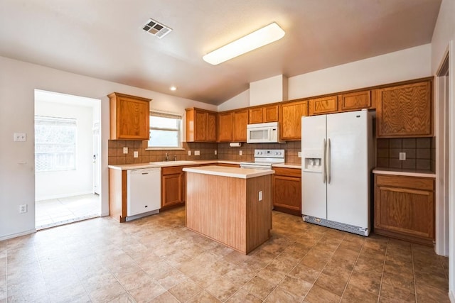 kitchen with brown cabinetry, visible vents, white appliances, and light countertops