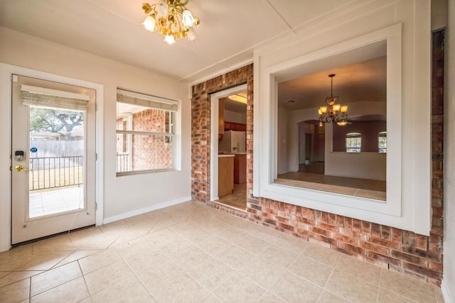 interior space featuring tile patterned floors, a notable chandelier, brick wall, and baseboards