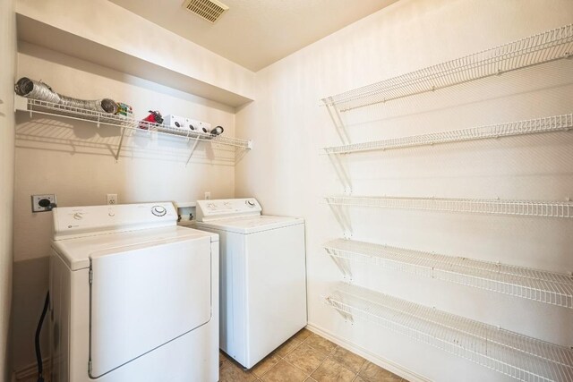 washroom featuring laundry area, light tile patterned floors, separate washer and dryer, and visible vents