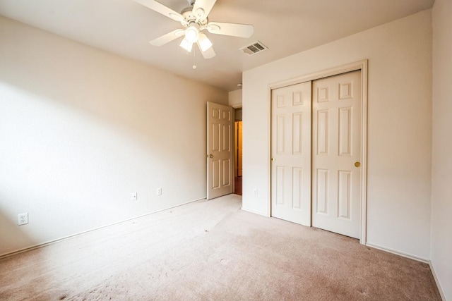 unfurnished bedroom with a ceiling fan, visible vents, a closet, and light carpet