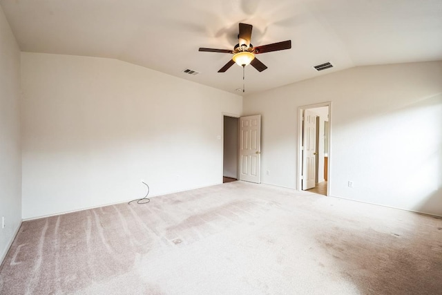 spare room featuring vaulted ceiling, carpet, and visible vents