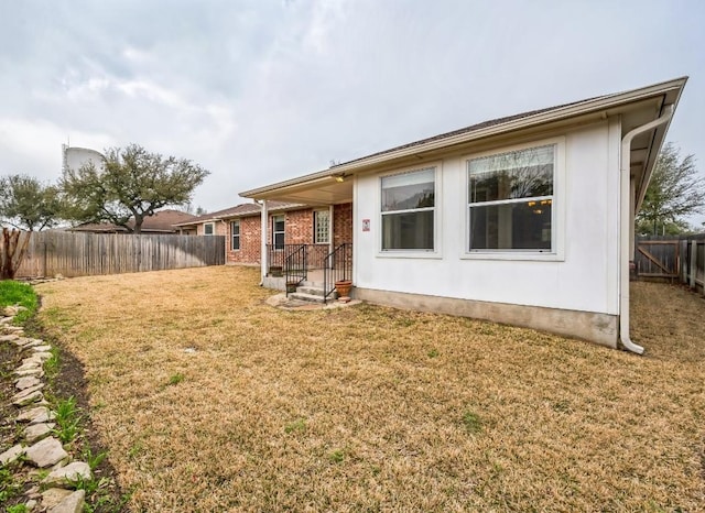 back of property featuring a yard, brick siding, and fence private yard