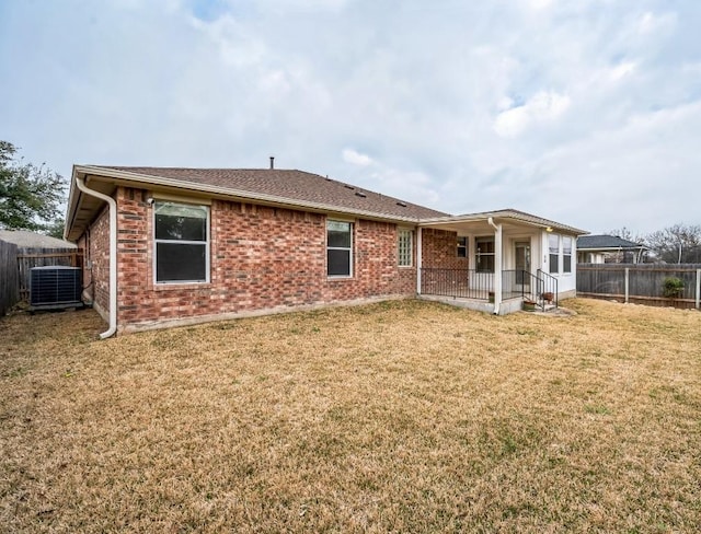 back of property featuring a yard, brick siding, cooling unit, and fence